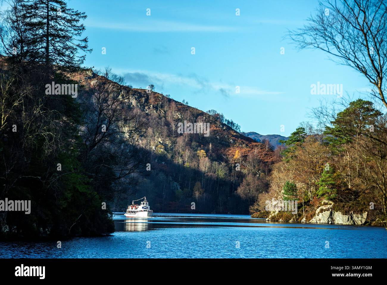 "Lady of the Lake", una barca turistica e da diporto, che si avvicina tra due promontori boscosi con una montagna alle spalle, in una giornata blu d'autunno sul Loc Foto Stock