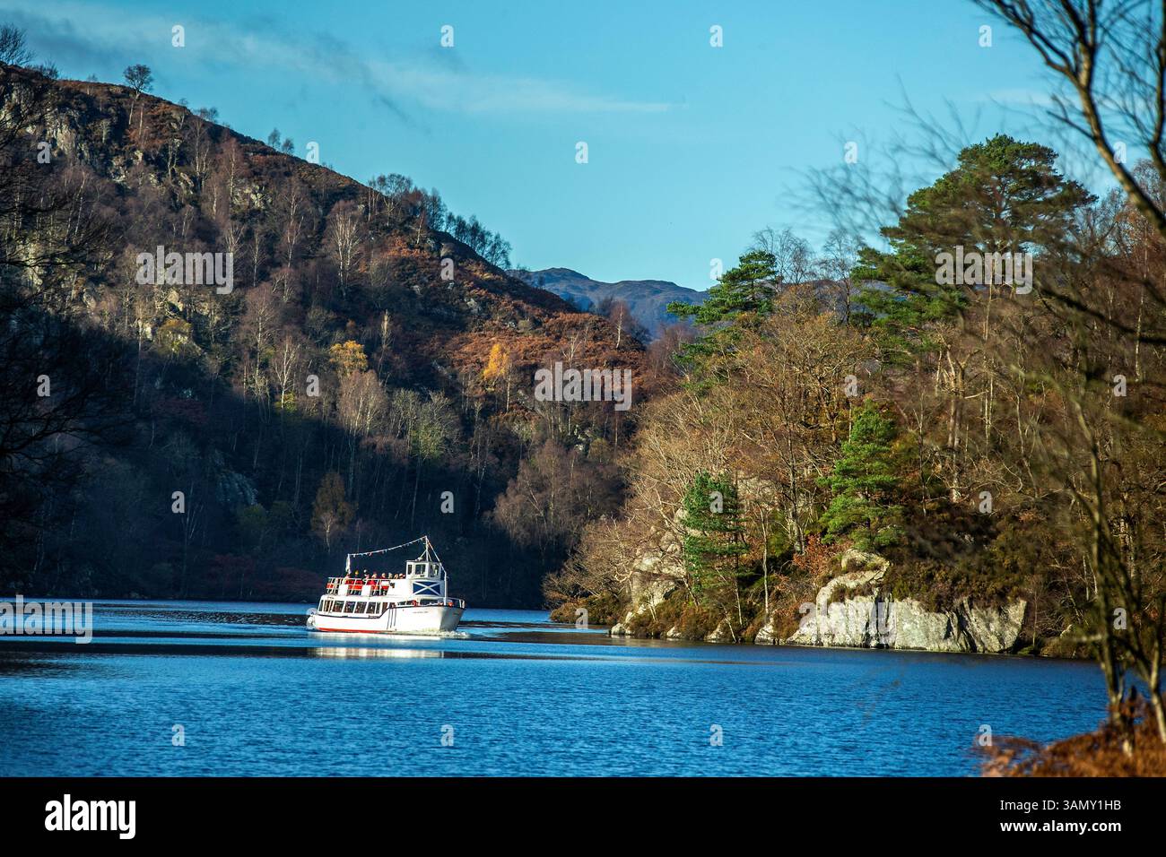 "Lady of the Lake", una barca turistica e da diporto, che si avvicina tra due promontori boscosi con una montagna alle spalle, in una giornata blu d'autunno sul Loc Foto Stock