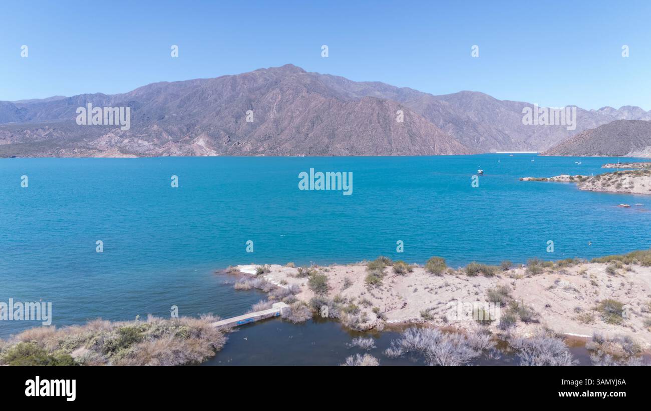 Vista aerea del tranquillo lago Potrerillos circondato da montagne maestose e cielo azzurro, Potrerillos, Mendoza, Argentina. Foto Stock