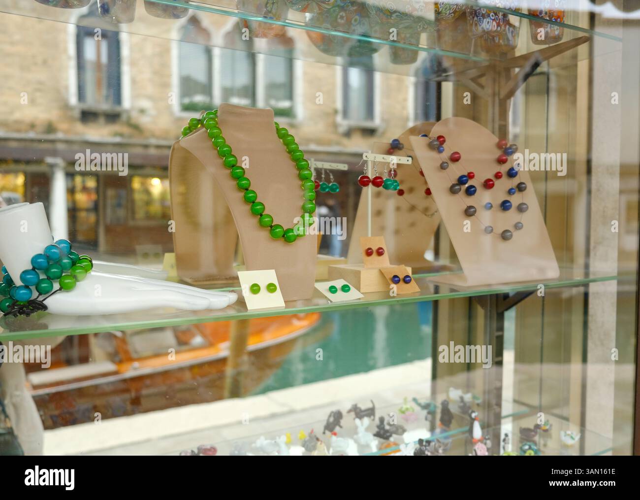 Vetrina di gioielli colorati in vetro di Murano in una vetrina. Include collana con perline verdi, orecchini e un bracciale con perline blu e verde. Foto Stock