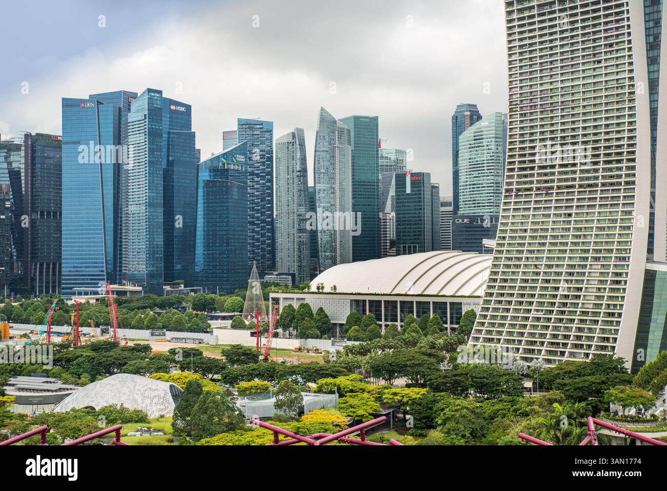 Un paesaggio urbano con alti edifici, alberi e gru visti dai Giardini della Baia di Singapore, nel sud-est asiatico Foto Stock