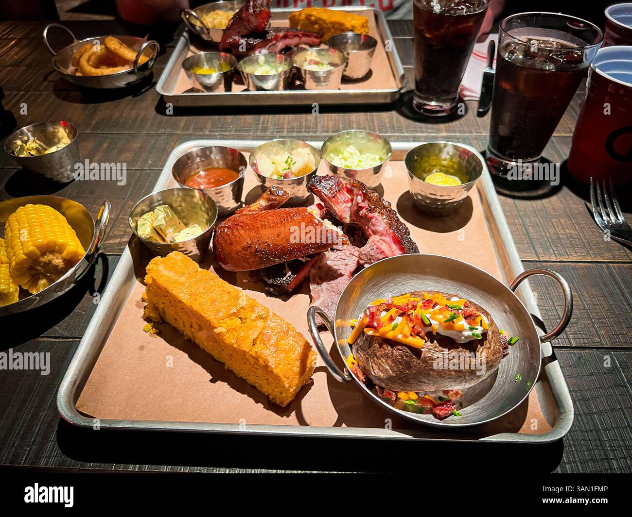 Un'abbondante festa al barbecue con pollo affumicato, costolette, petto, pane di mais, patate al forno, e tutti gli elementi di fissaggio sono serviti con i classici lati del sud e il viola - Immagine stock catturata con smartphone