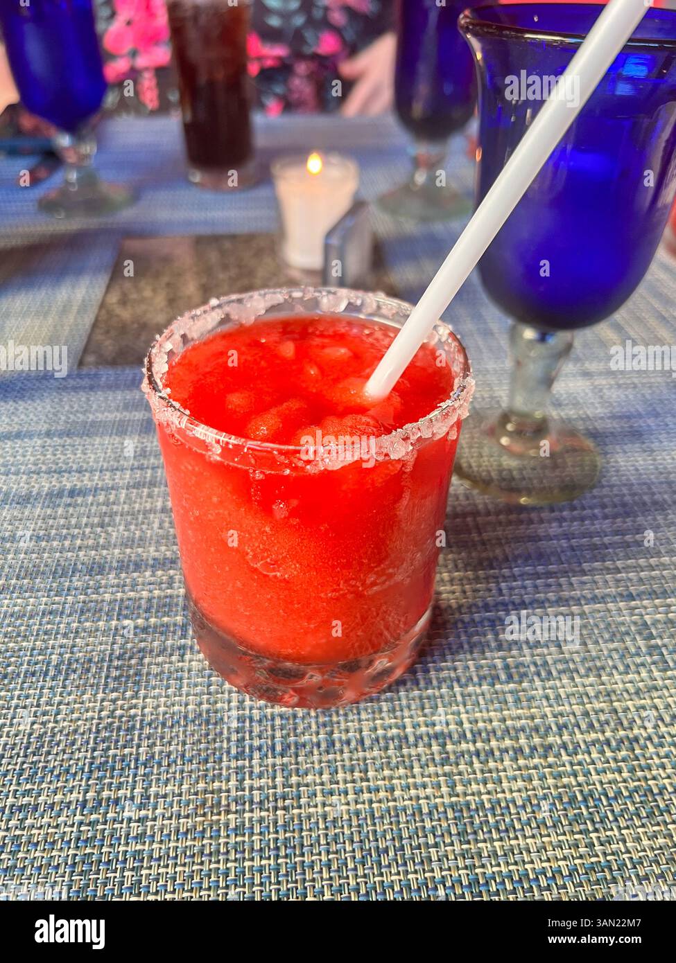 Un rinfrescante margarita di fragole ghiacciato servito con un bordo salato, perfetto per una fuga tropicale o per una serata rilassante in un ristorante. - Immagine stock catturata con smartphone