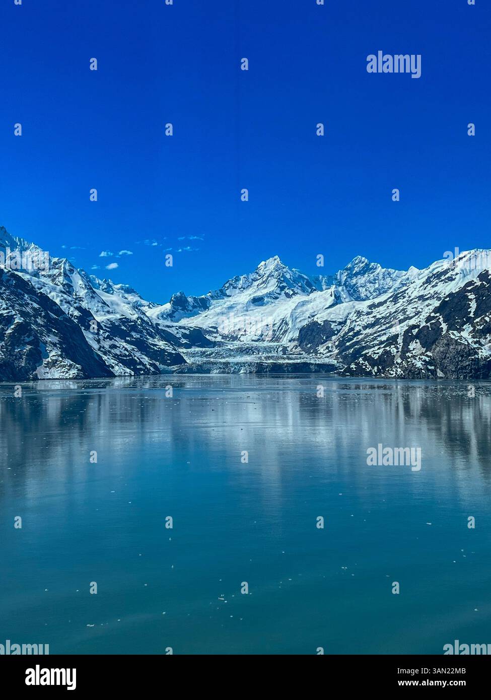 Le sfumature azzurre di questo ghiacciaio contrastano con le imponenti vette innevate, creando una maestosa scena artica. - Immagine stock catturata con smartphone