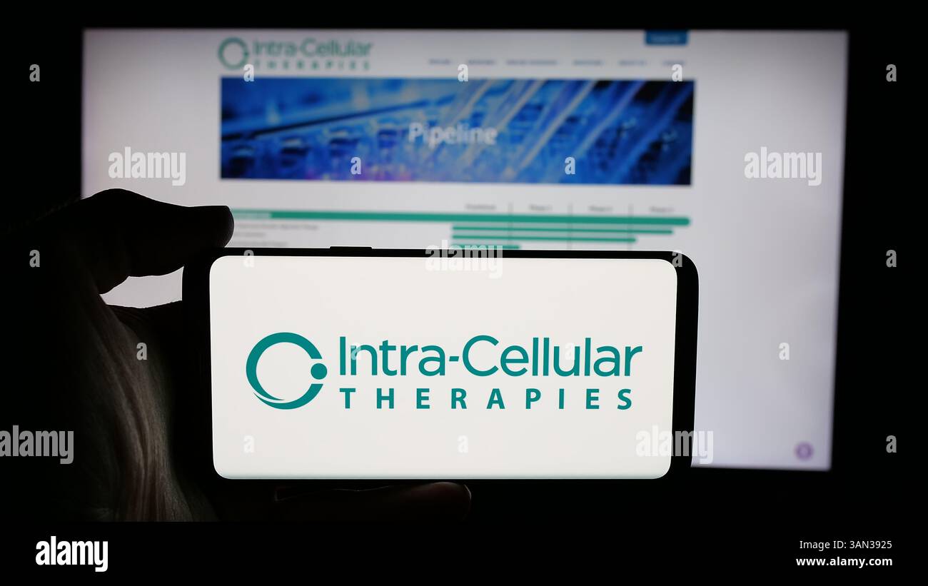 Stoccarda, Germania - 11-28-2024: Persona che tiene il cellulare con logo della società biotech americana Intra-Cellular Therapies Inc. Sullo schermo Foto Stock