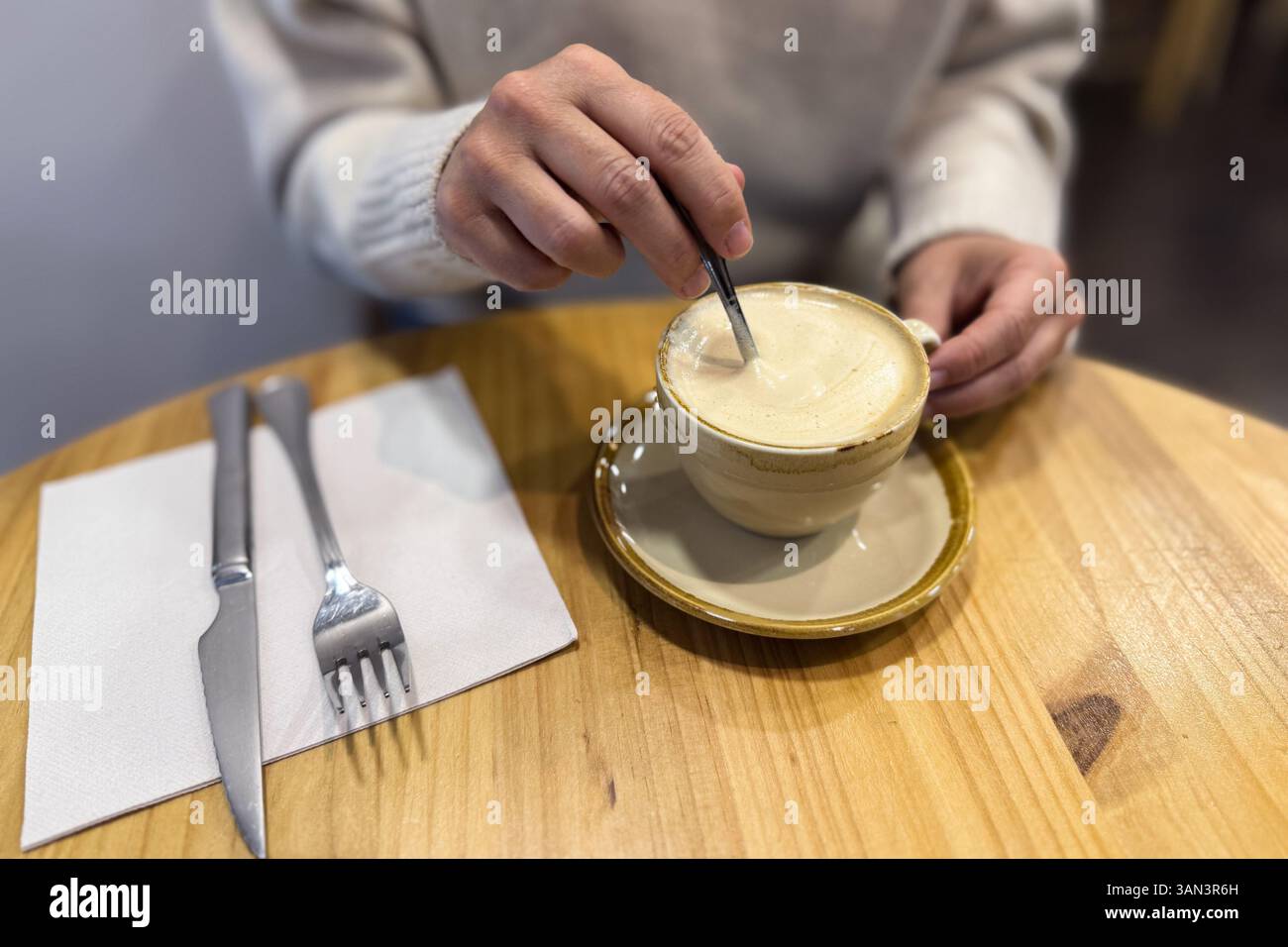 Mani di una donna che mescola un caffè su un tavolo del ristorante Foto Stock