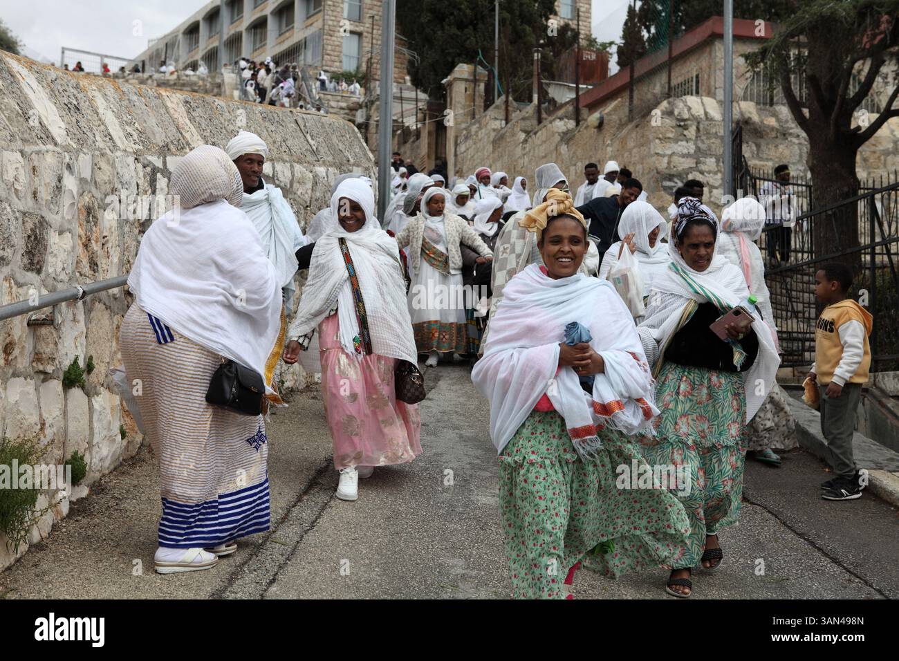Processione della domenica delle Palme, pellegrini cristiani etiopi principalmente donne e pochi bambini a piedi dal Monte Olive che commemorano la corsa di Cristo su una colata fino a Gerusalemme. Foto Stock