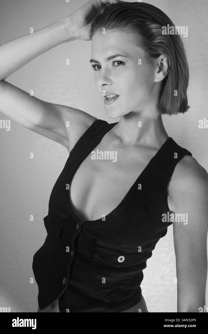 Ritratto in bianco e nero di una modella che indossa un gilet nero, un elegante trucco e capelli. Headshot in studio di una giovane bella donna sicura di sé, Foto Stock