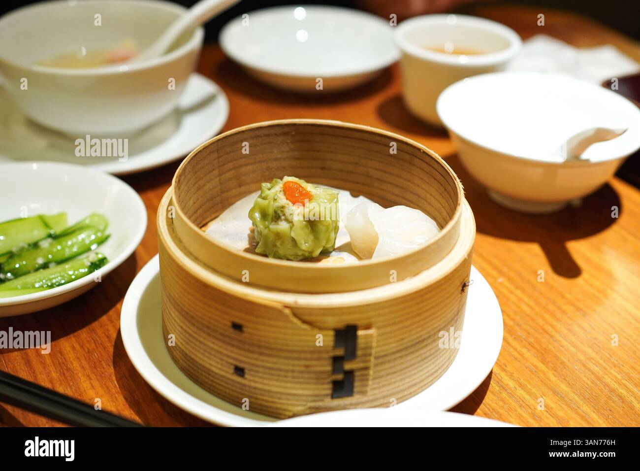 Spinaci appena cotti Shumai (guanciali al vapore) e xiao rong bao in una vaporiera di bambù Foto Stock