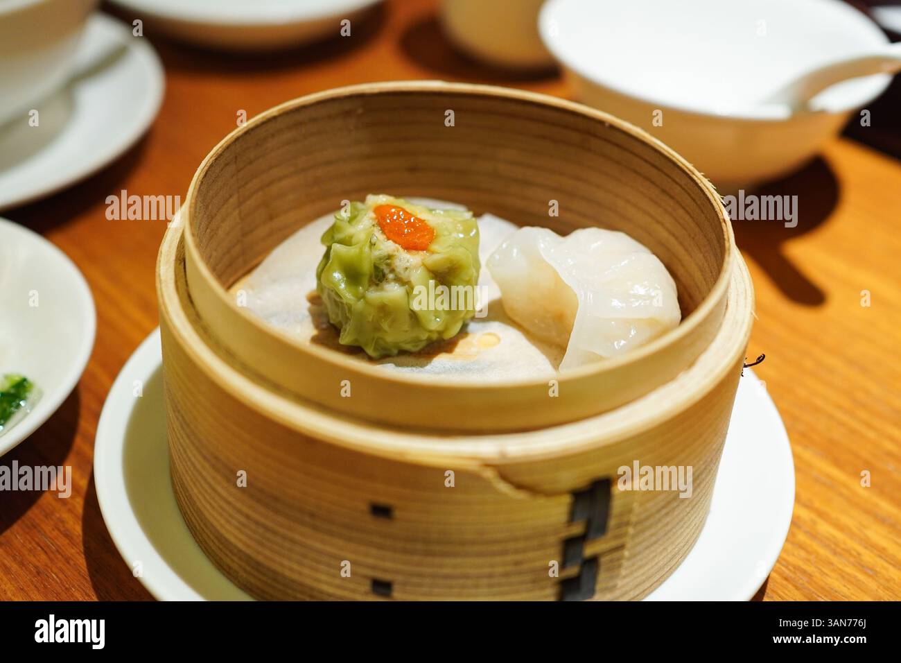 Spinaci appena cotti Shumai (guanciali al vapore) e xiao rong bao in una vaporiera di bambù Foto Stock