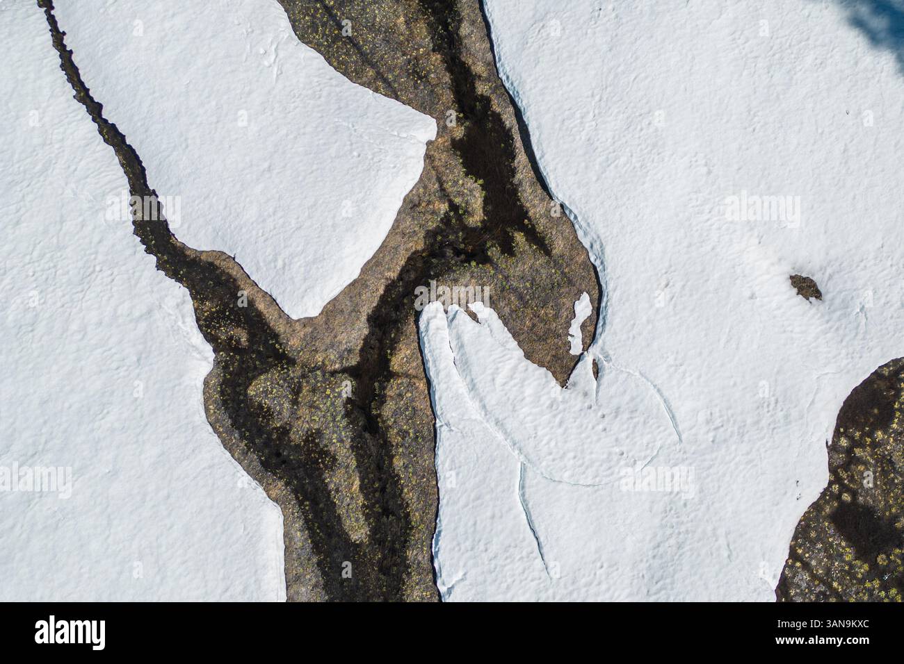 Una vista aerea con drone prospettico di ciaspole che si sciolgono in primavera e fluiscono dall'acqua dalla neve sciolta nel nord della California. Foto Stock