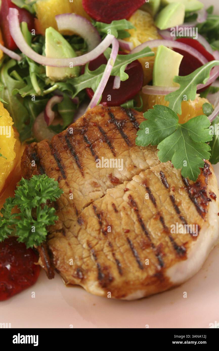 Maiale con zucca e insalata di arancia e barbabietole e avocado Foto Stock