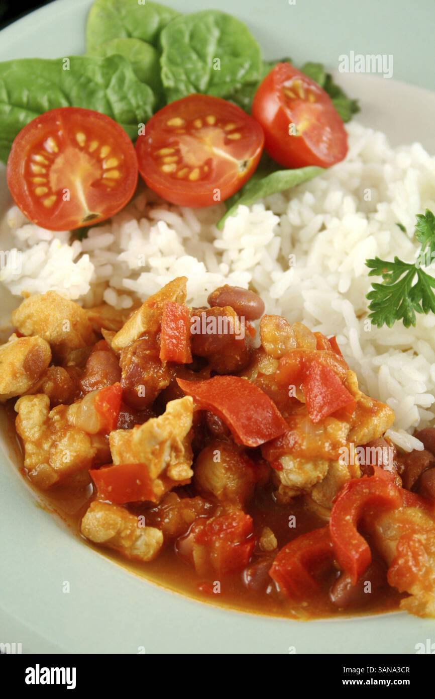Stufato speziato di lenticchie di pollo e pepe con riso e insalata fresca Foto Stock