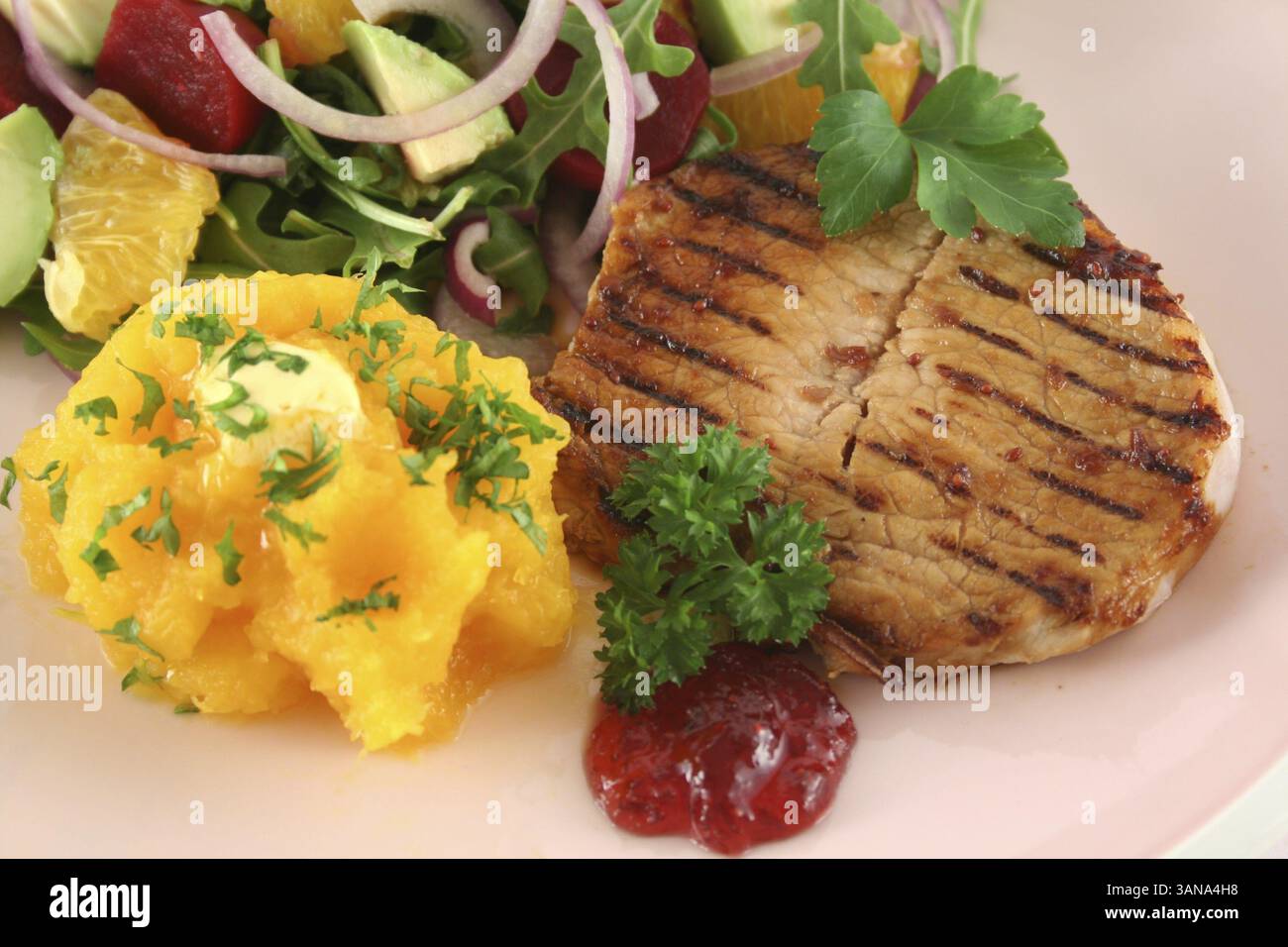 Maiale con zucca e insalata di arancia e barbabietole e avocado Foto Stock