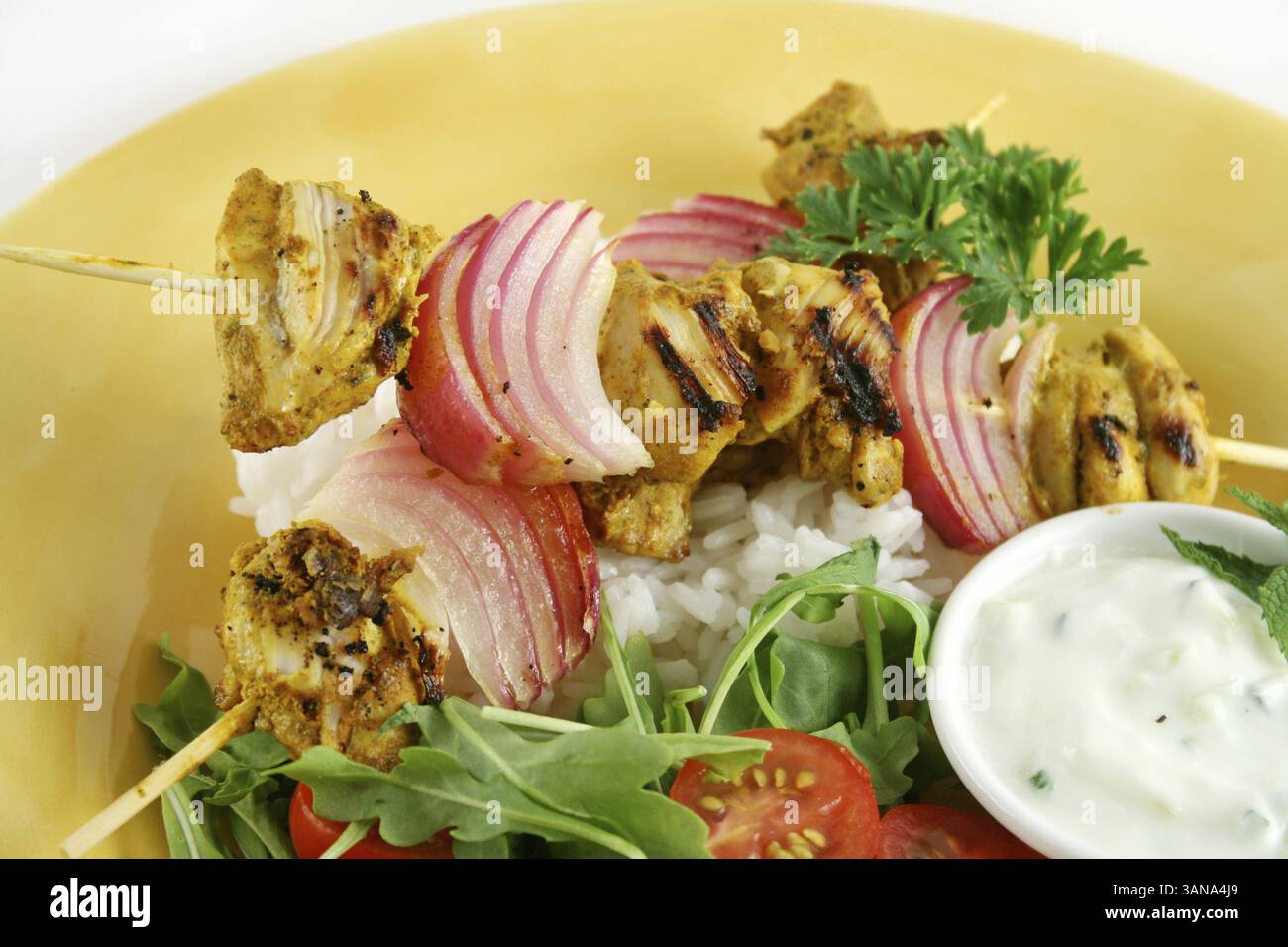 Spiedini di pollo tandoori con yogurt alla menta e un'insalata di rucola Foto Stock