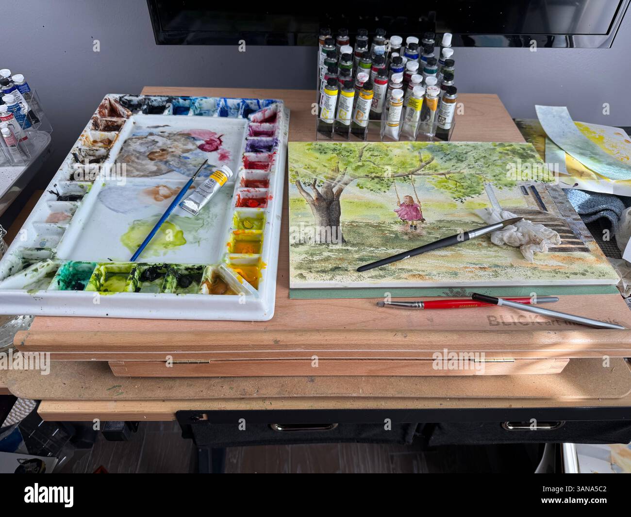 Scrivania artistica di un artista acquerello che mostra tubi di vernice, una tavolozza, pennelli e un dipinto ad acquerello incompiuto. STATI UNITI Foto Stock