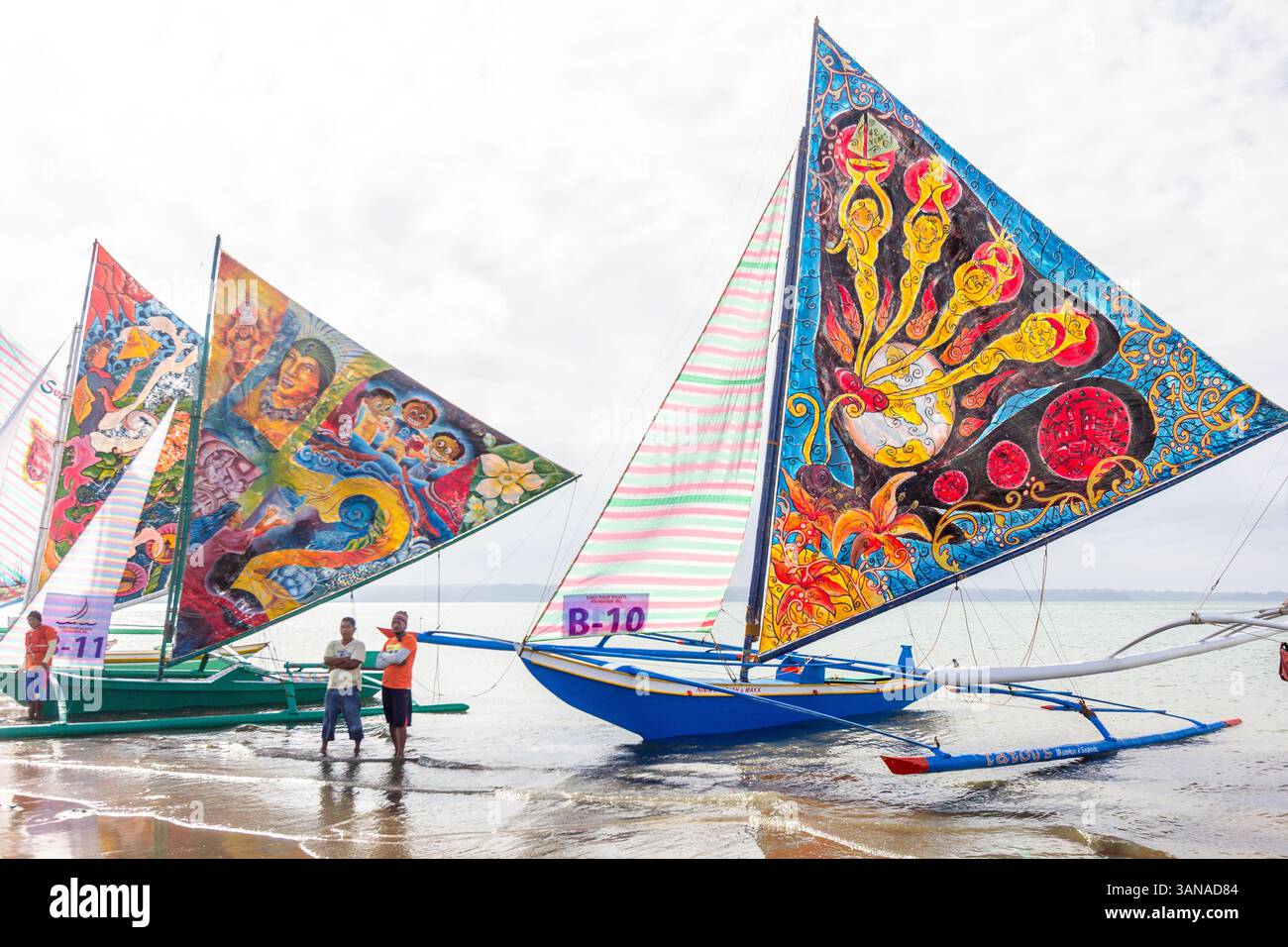 I Paraws, o le barche locali filippine con enormi vele colorate colorate, fiancheggiano la spiaggia durante il Paraw Festival di Iloilo, Filippine Foto Stock