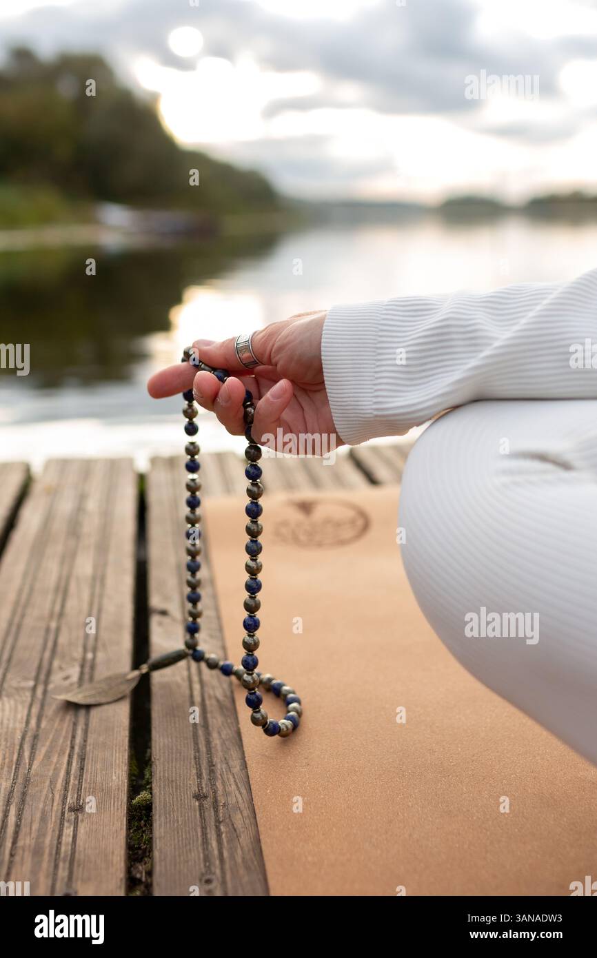 Donna, mano illuminata da vicino, conti Malas, fili di perle di legno utilizzate per tenere il conto durante le meditazioni sui mantra. Induismo e Japa mala buddista. PRA Foto Stock
