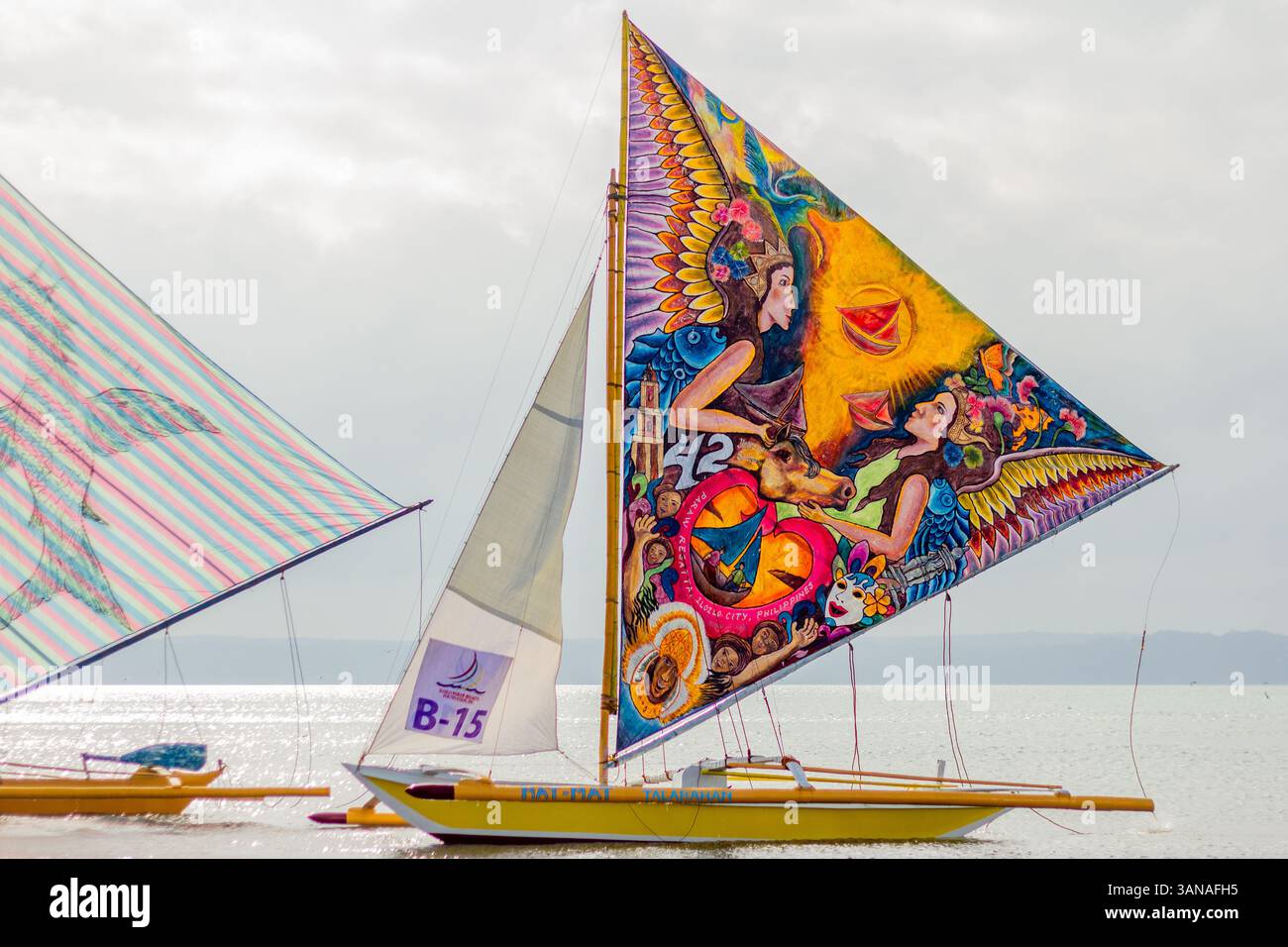 I Paraws, o le barche locali filippine con enormi vele colorate colorate, fiancheggiano la spiaggia durante il Paraw Festival di Iloilo, Filippine Foto Stock