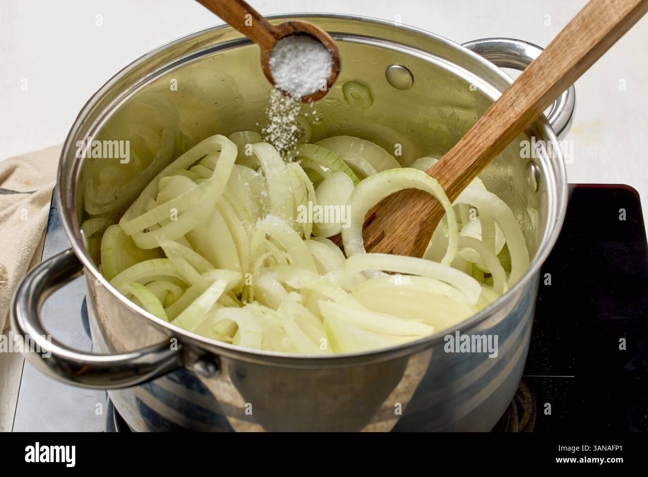 cuocere aggiungere il sale in un recipiente di cipolle fresche tagliate a fette e preparare la zuppa di cipolle Foto Stock