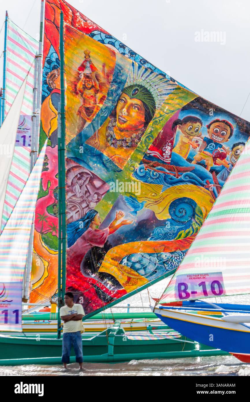 I Paraws, o le barche locali filippine con enormi vele colorate colorate, fiancheggiano la spiaggia durante il Paraw Festival di Iloilo, Filippine Foto Stock