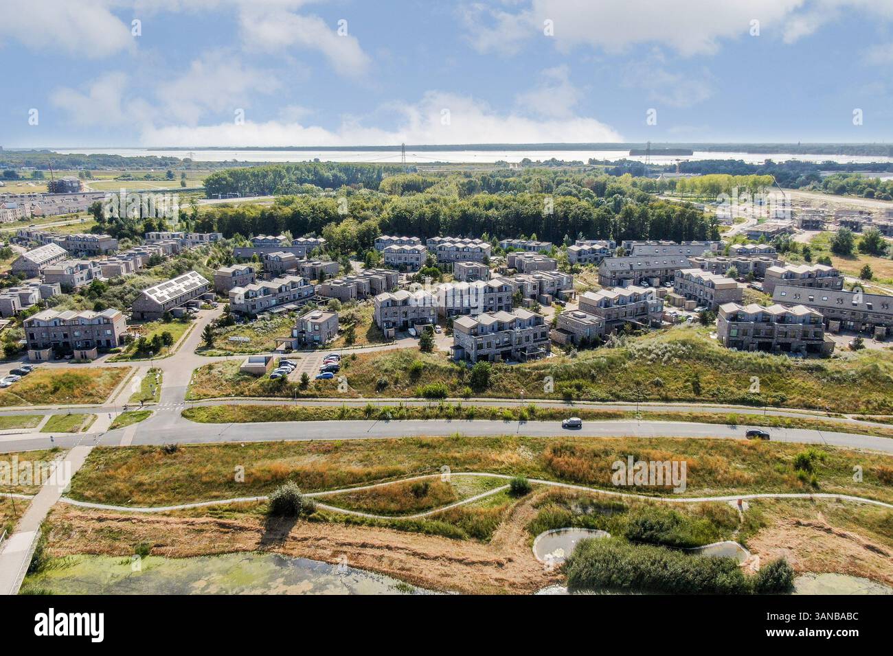 Ampia vista aerea che mostra un'area residenziale ben progettata con case, vegetazione e strade, circondata da sereni paesaggi naturali. Foto Stock