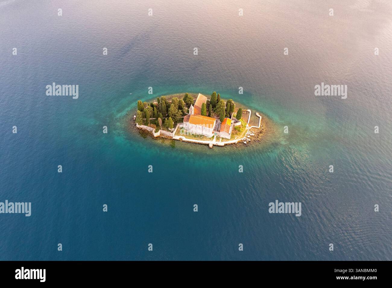 Vista aerea del tranquillo monastero cattolico di San Giorgio su una pittoresca isola circondata da tranquille acque turchesi, dalla baia di Cattaro, Montenegro. Foto Stock