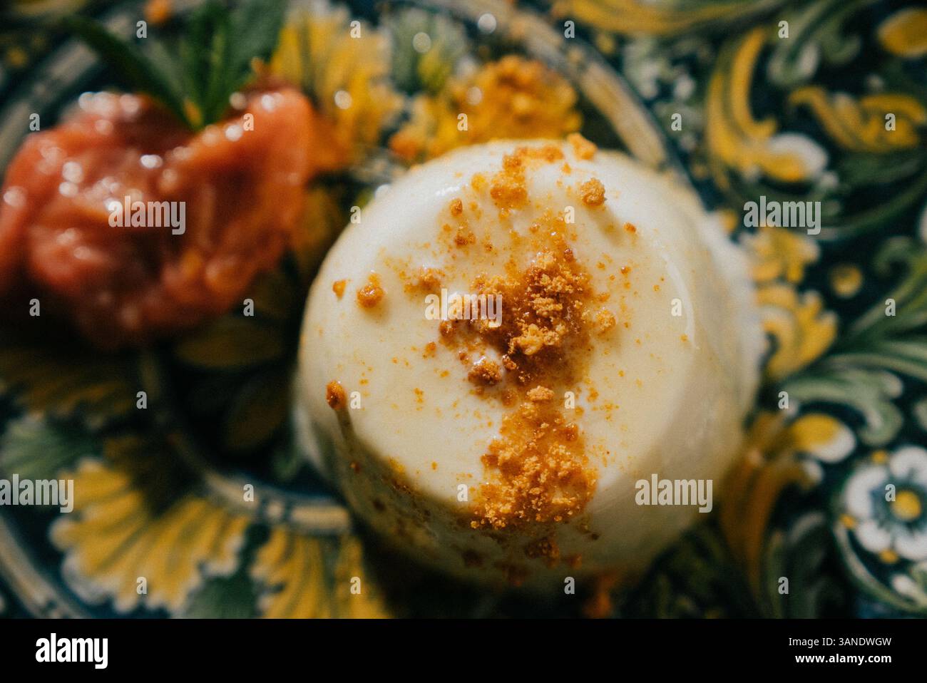 Un dessert con un condimento di briciole e una salsa sopra. Il dessert è su un piatto con sfondo giallo Foto Stock