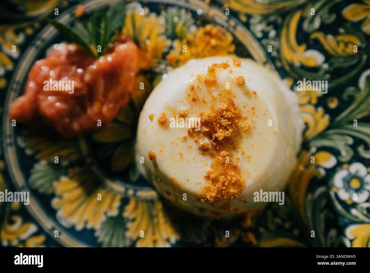 Un dessert con un condimento di noci e una salsa sopra. Il dessert è su un piatto con un motivo giallo e verde Foto Stock