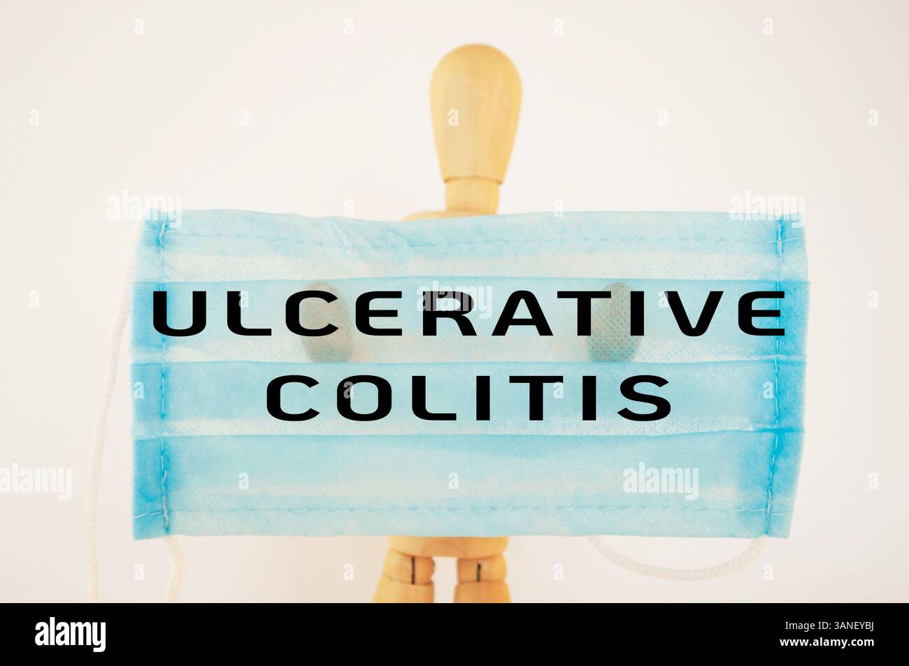 L'uomo ha in mano una maschera chirurgica blu con le parole colite ulcerosa Foto Stock
