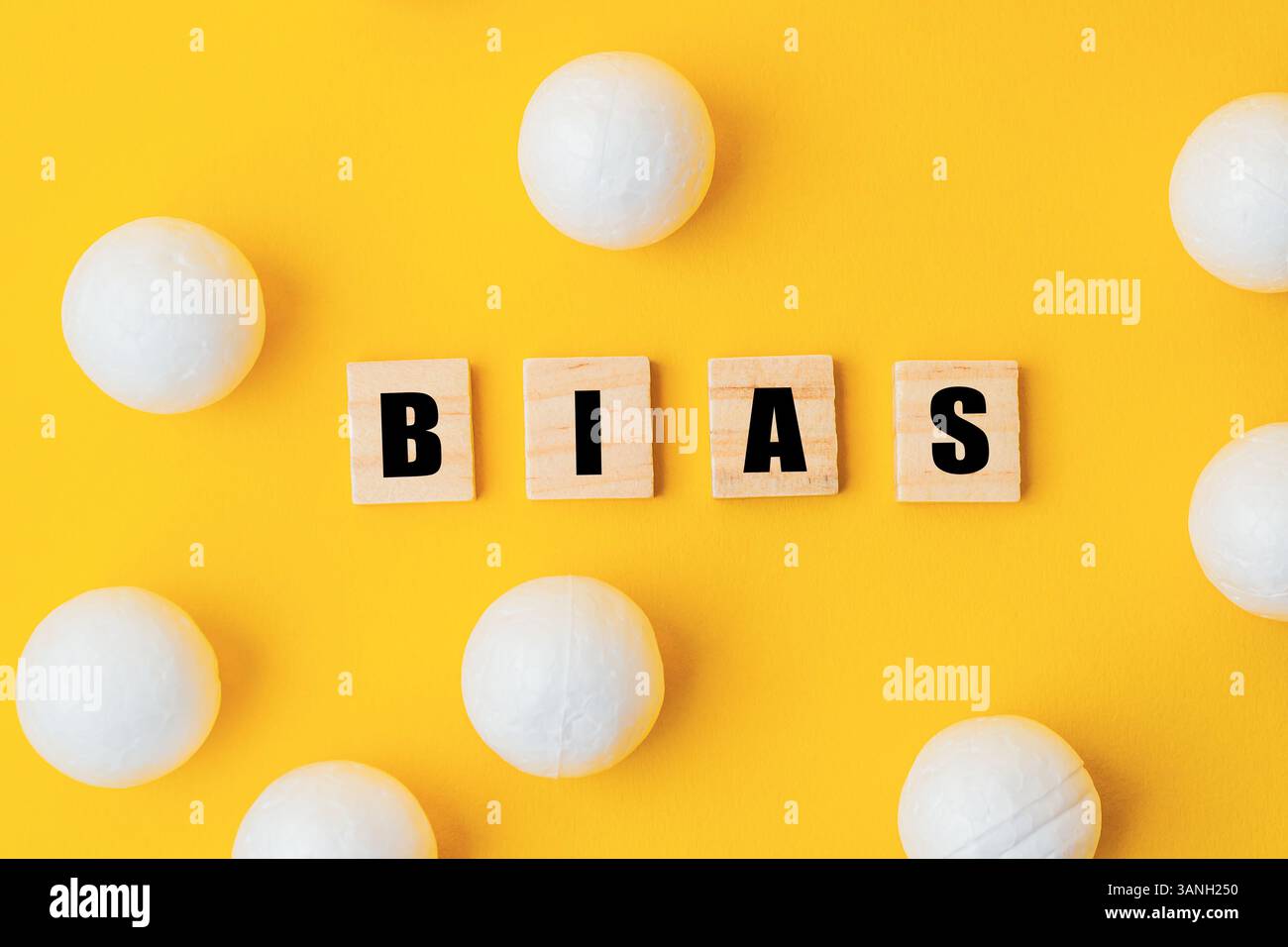 Sfondo giallo con lettere bianche che scrivono la parola "bias" in un carattere di blocco di legno. Le lettere sono circondate da palline bianche, creando un playfu Foto Stock