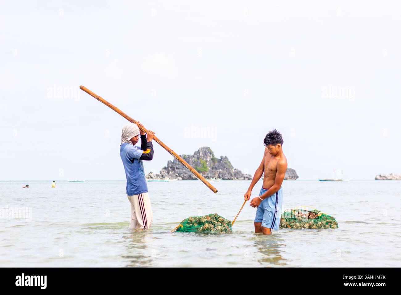 Pescatori filippini che trasportano conchiglie di capesante raccolte da barca a riva nelle isole Gigantes, Iloilo, Filippine Foto Stock