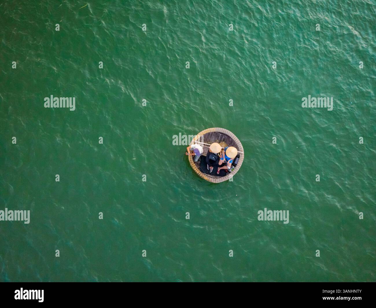 Vista aerea di tre persone che navigano su una piccola barca da cocco con i tipici cappelli vietnamiti sul fiume Thu Bon, Quảng Nam, Vietnam. Foto Stock