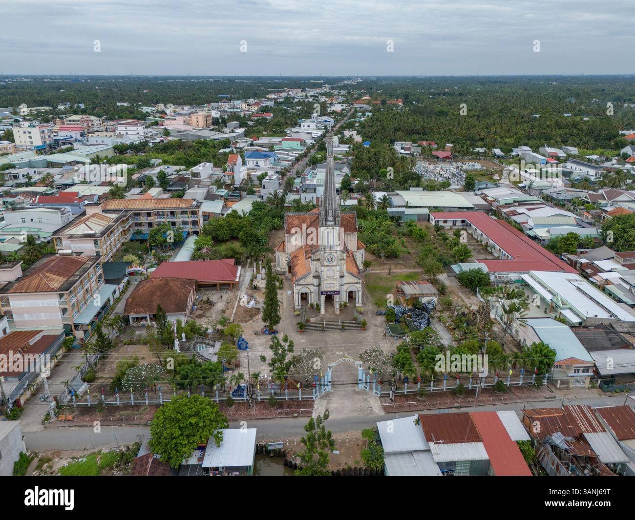 Vista aerea del vivace paesaggio urbano con edifici tradizionali e moderni, vegetazione lussureggiante e uno skyline tranquillo, Cai Be, Tien Giang, Vietnam. Foto Stock
