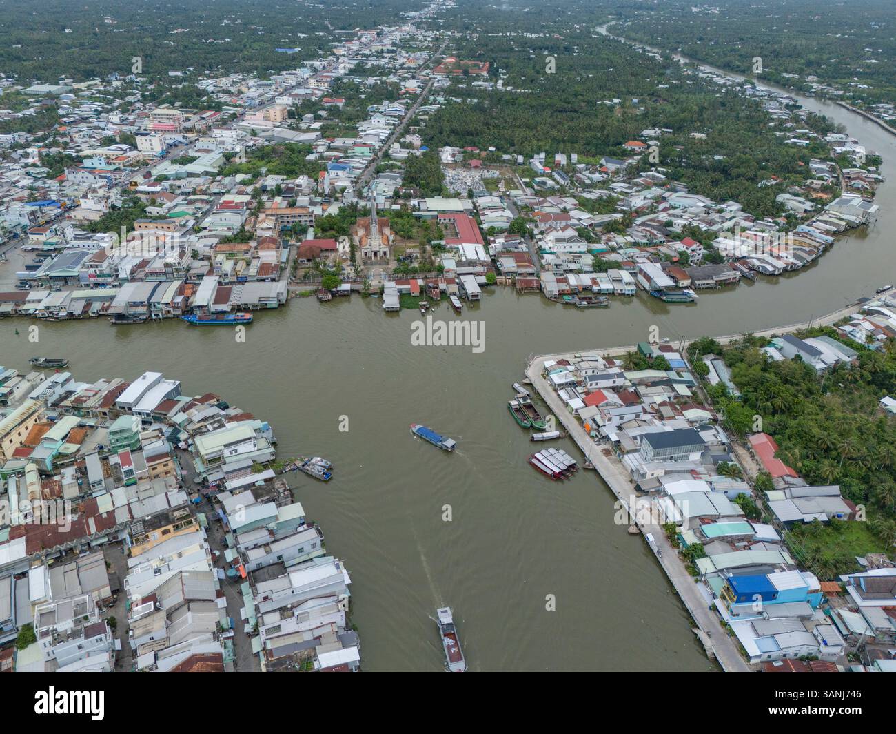 Vista aerea di un bellissimo quartiere residenziale urbano con edifici e barche lungo il fiume, Cai Be, Tien Giang, Vietnam. Foto Stock