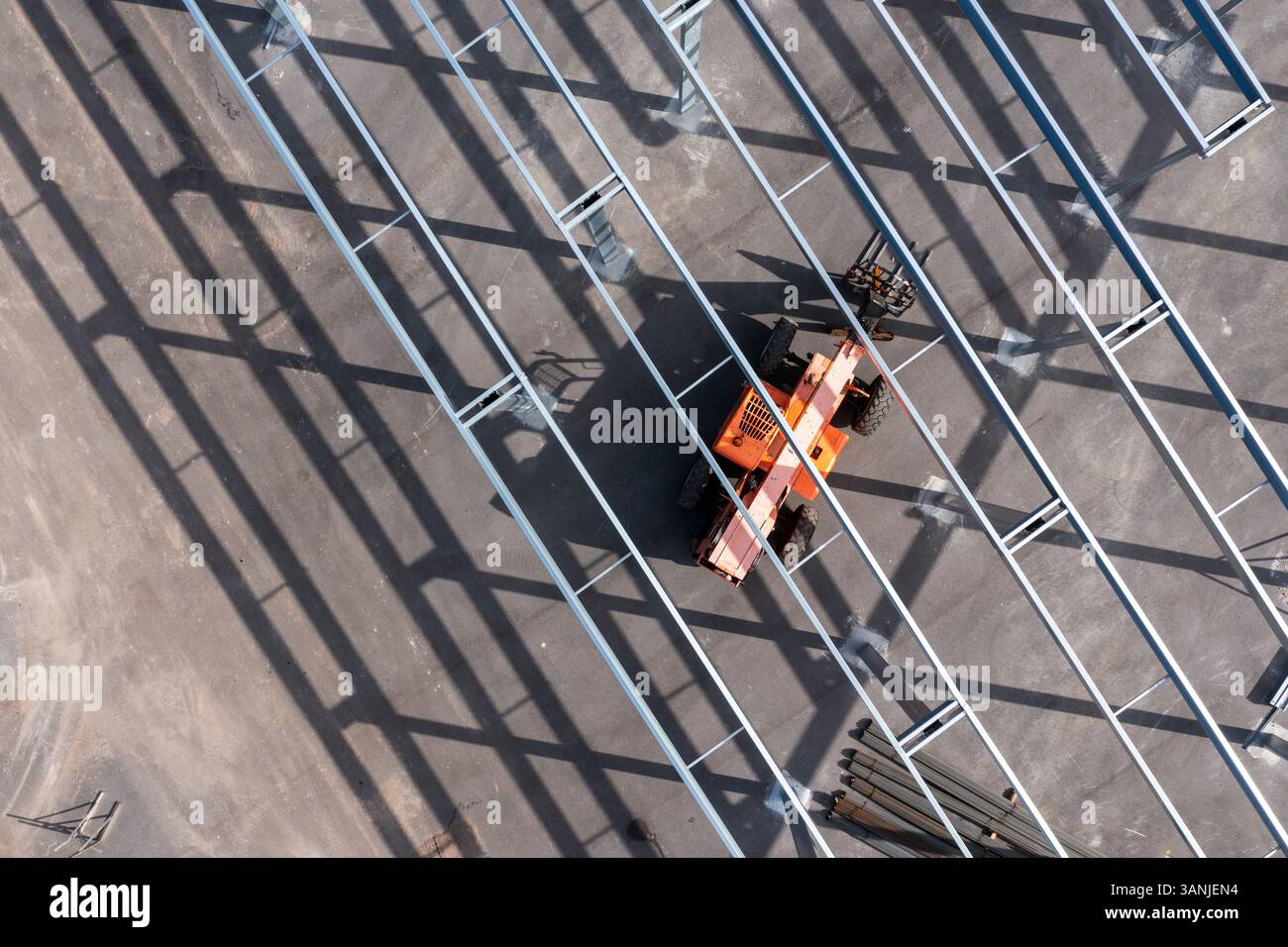 Vista aerea di travi metalliche e ombre in un cantiere con un veicolo arancione, Wabasso, Florida. Foto Stock