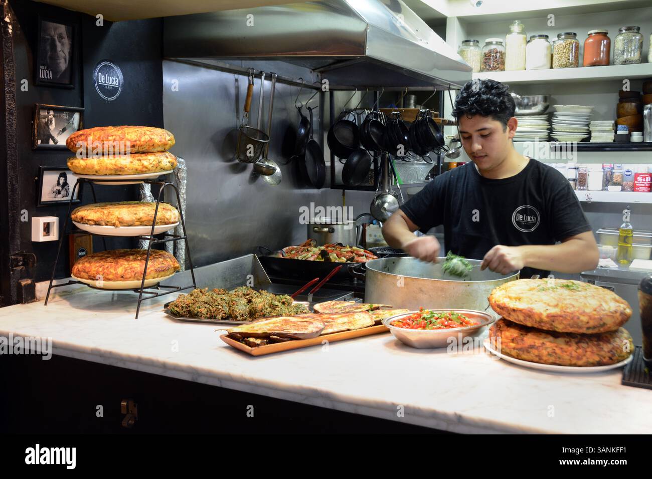 Un commerciante alimentare che produce frittelle di verdure e vende tortilla di papas, una frittata di uova e patate nel mercato di San Telmo a Bueno Aires, Argentina. Foto Stock