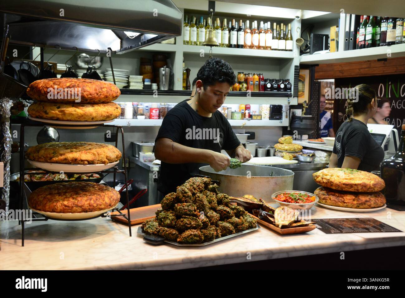 Un commerciante alimentare che produce frittelle di verdure e vende tortilla di papas, una frittata di uova e patate nel mercato di San Telmo a Bueno Aires, Argentina. Foto Stock