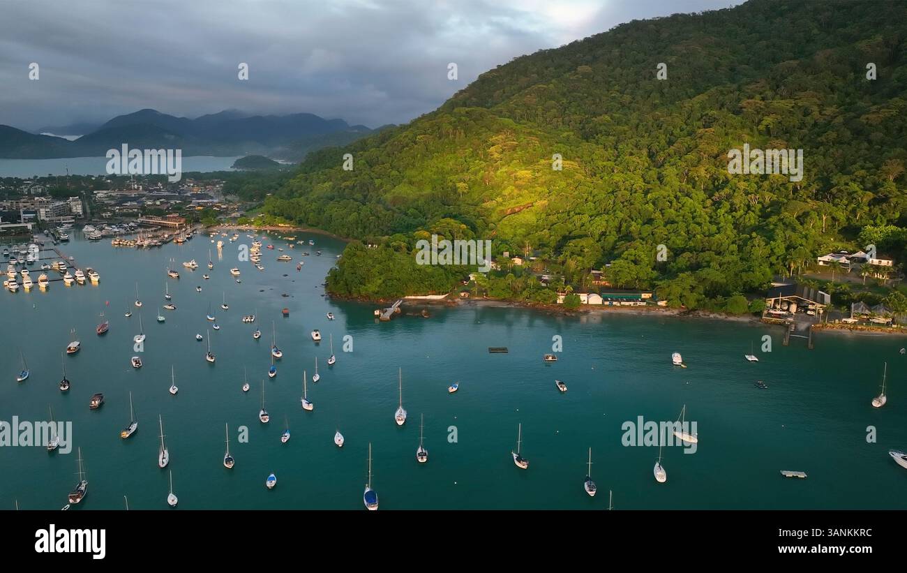 Vista aerea dell'arcipelago tropicale con isole tranquille e barche nell'oceano calmo sotto le nuvole all'alba, Angra dos Reis, Brasile. Foto Stock