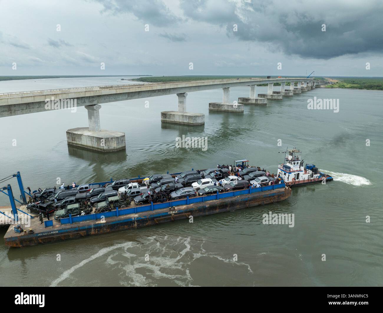 Vista aerea delle auto sul transito in acqua con un ponte su un fiume, Bonny, Nigeria. Foto Stock