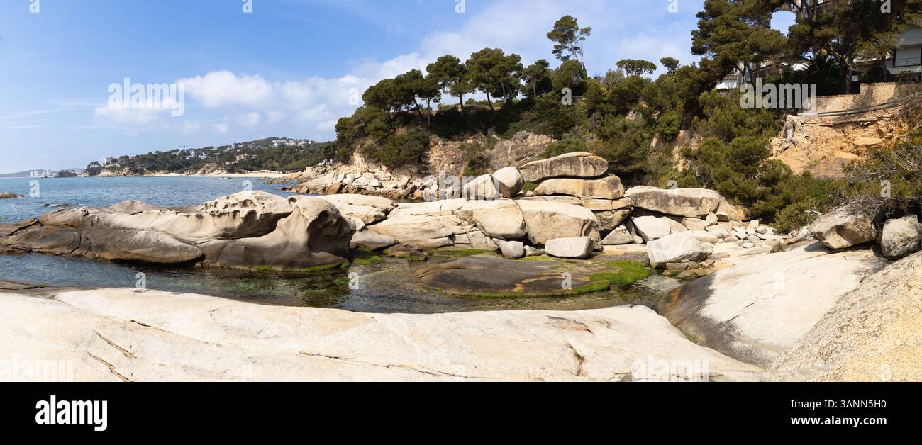vista panoramica degli aerei di Punta Rocas, Costa Brava, con le sue dolci formazioni rocciose, le piscine d'acqua con alghe e le scogliere ricoperte di pini. Foto Stock