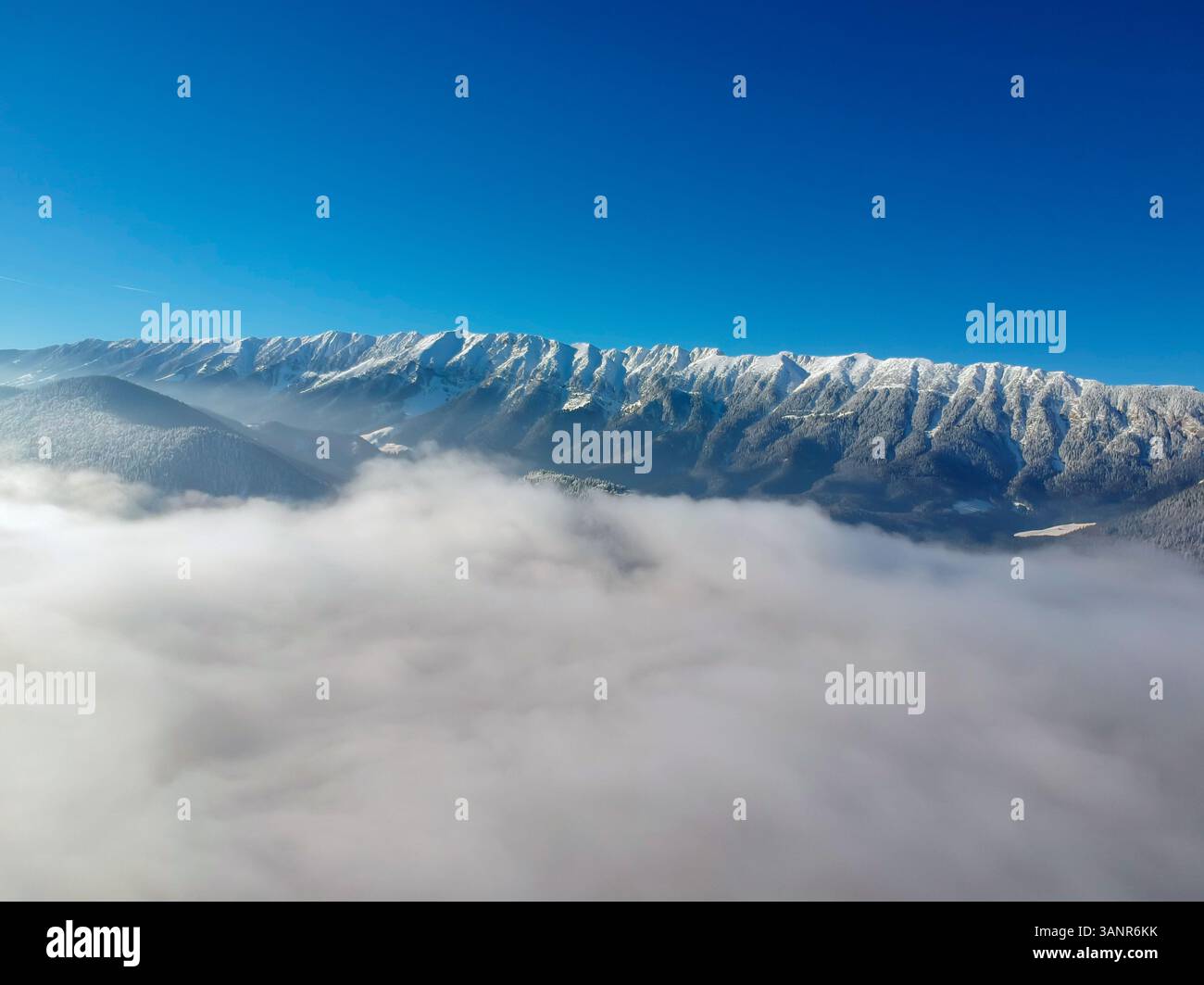 Vista aerea delle montagne di Piatra Craiului dall'alto delle nuvole del parco nazionale di Piatra Craiului, Brasov, Romania Foto Stock