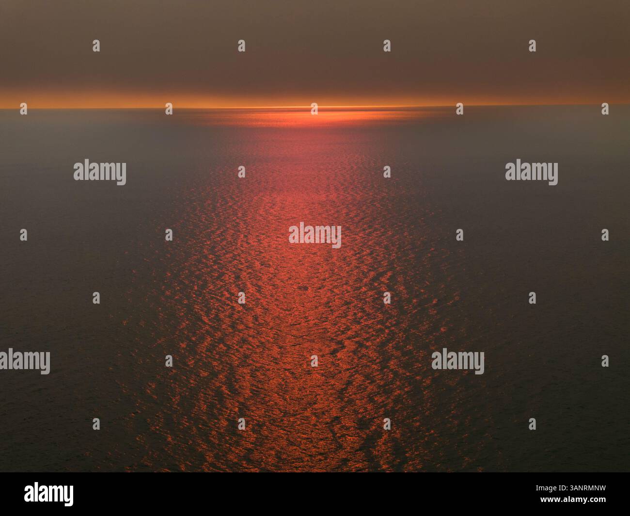 Vista aerea del tramonto fumoso con riflesso del sole sul mare calmo, Scarborough, Australia. Foto Stock