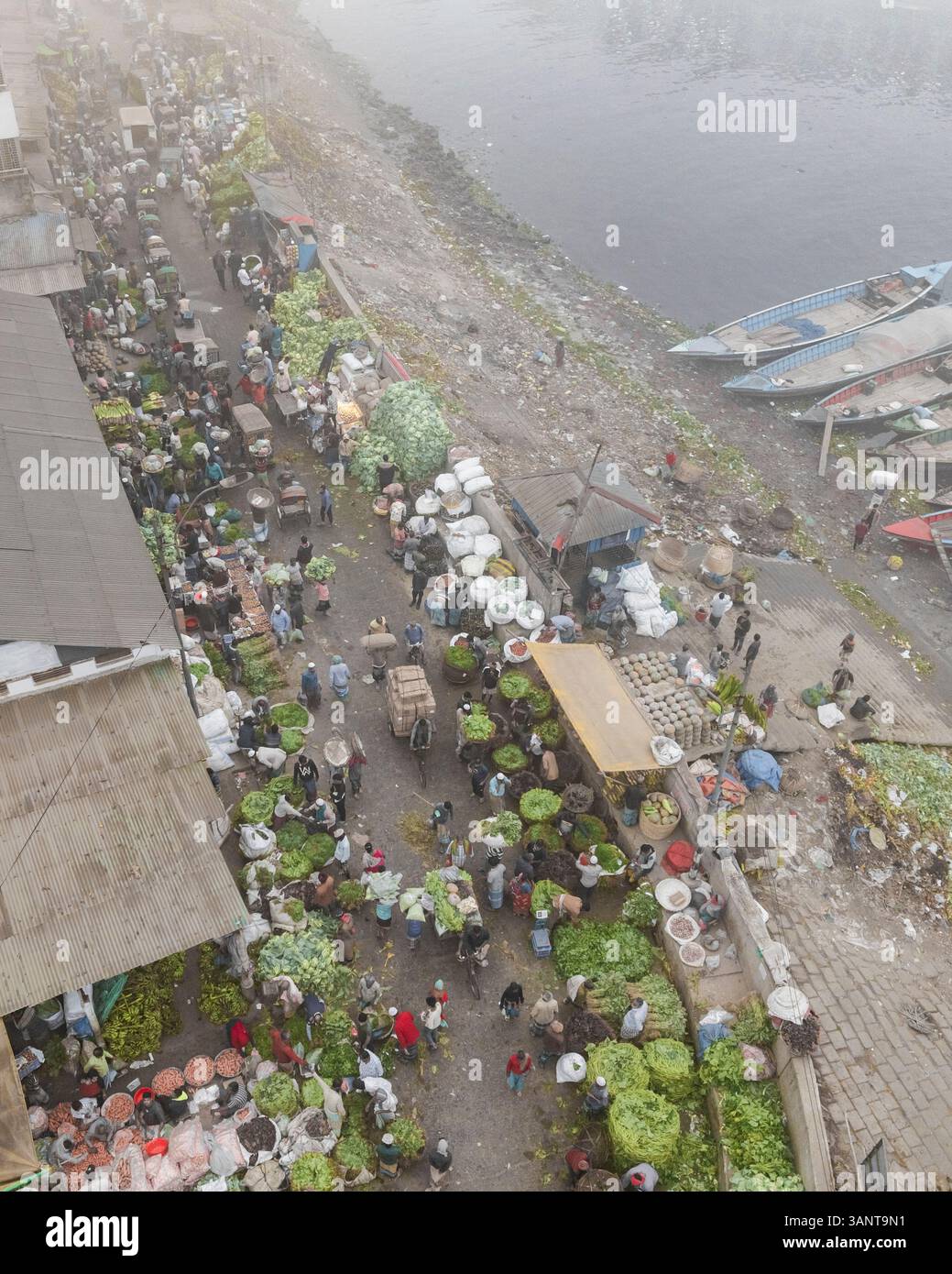 Vista aerea di un vivace mercato di verdure con venditori e barche lungo la riva del fiume, Sutrapur Thana, Dacca, Bangladesh. Foto Stock