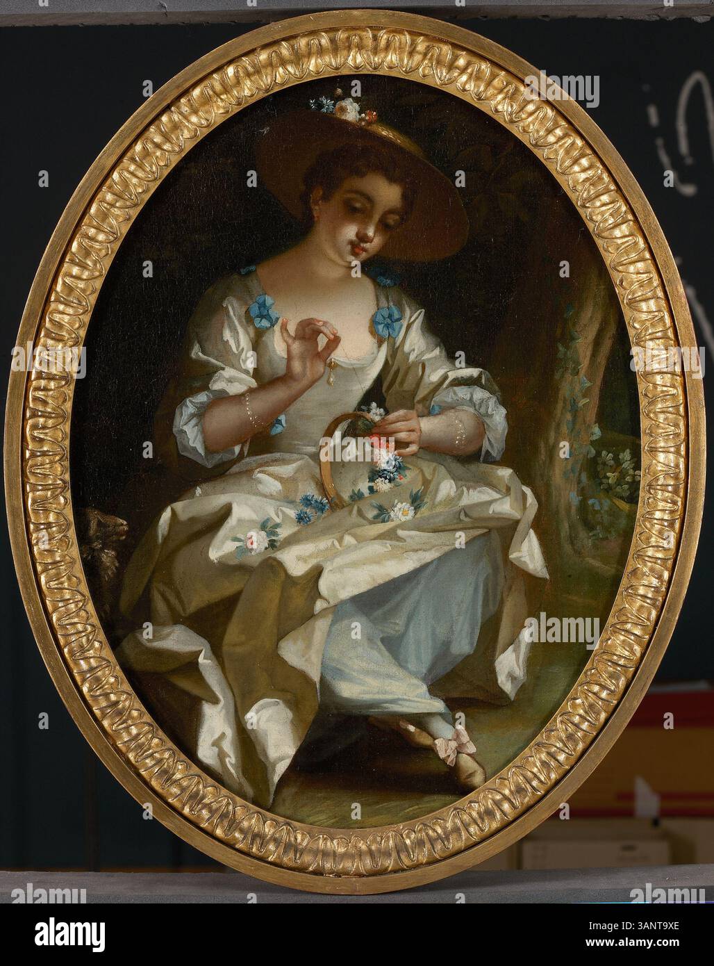 Attribuito a Jean Raoux o al suo seguace, questo dipinto del XVIII secolo ritrae una giovane signora che crea una corona di fiori, che mostra l'arte di genere tipica del periodo. Dipinto tra il 1700 e il 1749, riflette lo stile Rococò con la sua attenzione alla vita quotidiana e ai dettagli delicati. Foto Stock