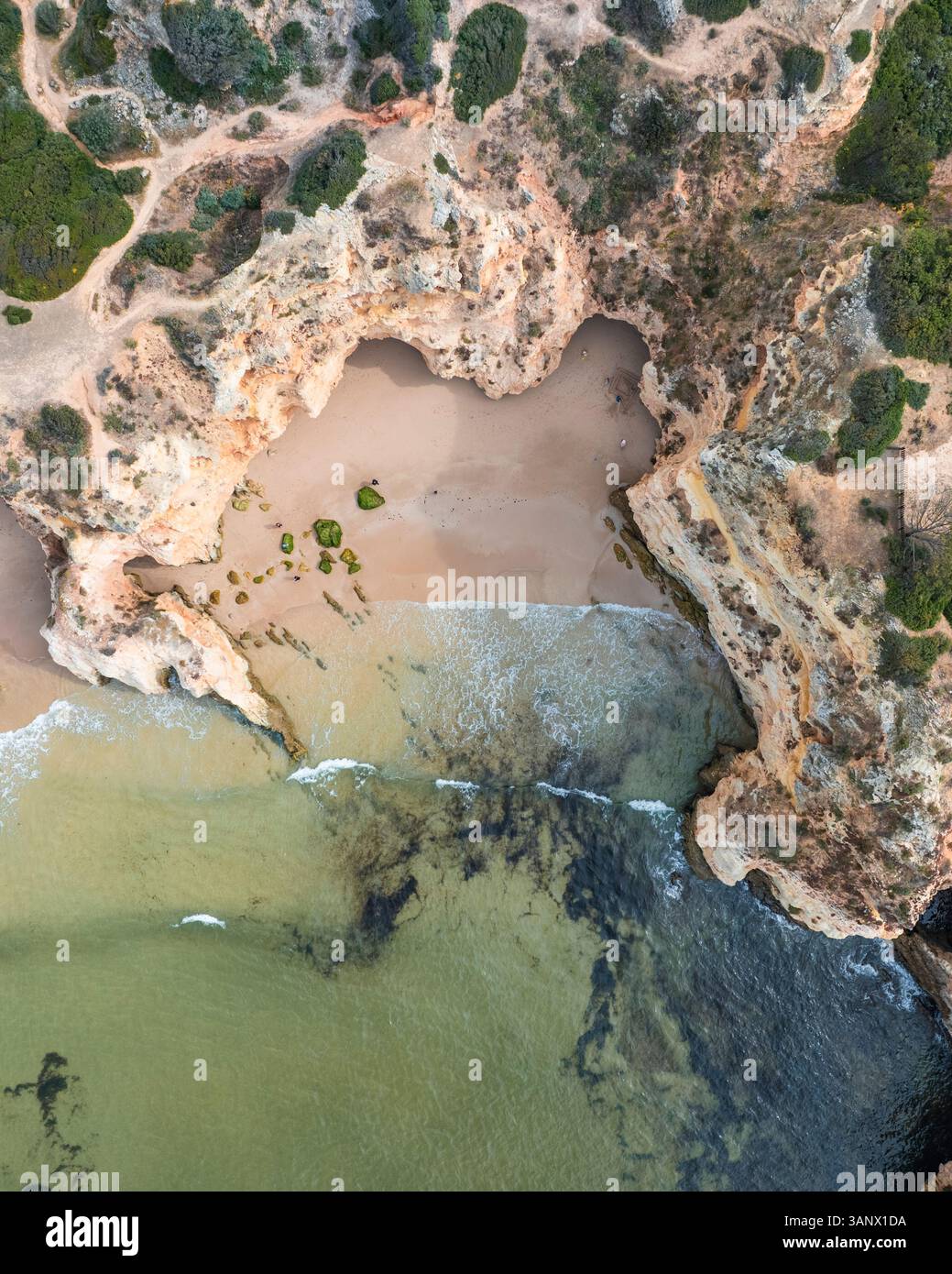 Vista aerea della costa frastagliata con scogliere e insenature a Praia dos Tres Irmaos, Alvor, Algarve, Portogallo. Foto Stock