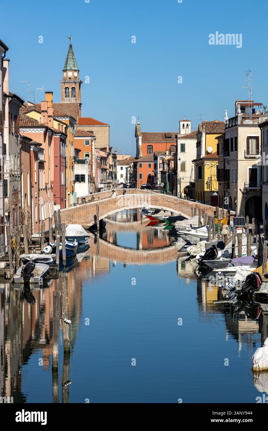 Chioggia, Italia - 3 marzo 2025: Veduta del Canal Vena con barche ormeggiate, un ponte pedonale e riflessi nel centro storico della città Foto Stock