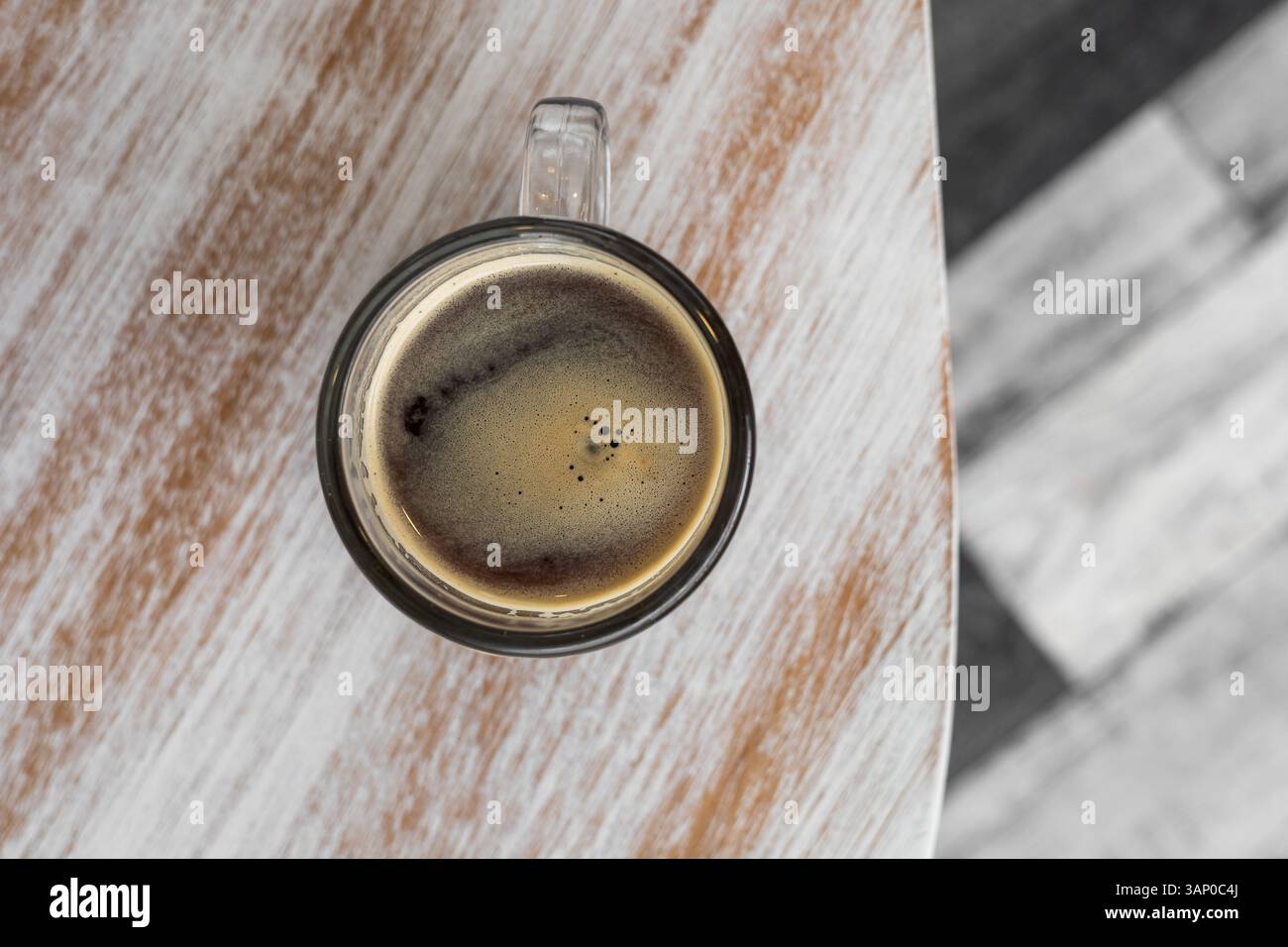 Una tazza da caffè siede su un tavolo di legno con sfumature di crema e miele, mettendo in risalto i cereali naturali e un'atmosfera accogliente e invitante. Foto Stock