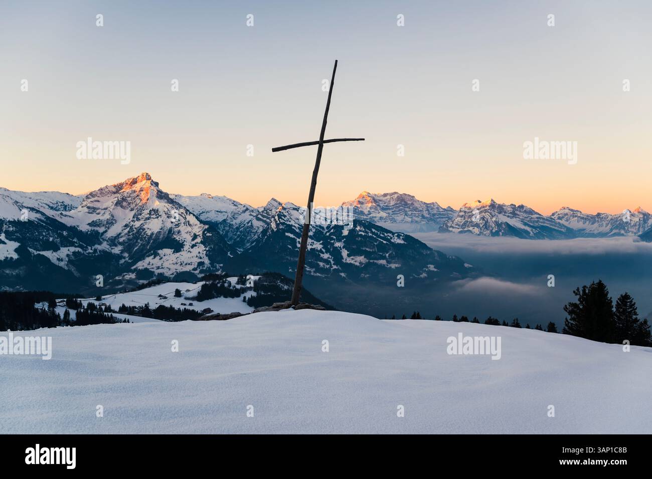 Una croce di legno di fronte al panorama delle Alpi Glariche innevate all'alba, San Gallo, Glarona, Svizzera Foto Stock