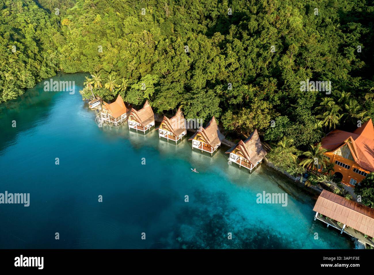 Vista aerea di persone con una canoa lungo il bungalow sull'acqua di un resort di lusso nella giungla a Bucas grande, Sohoton Cove, Siargao Filippine. Foto Stock